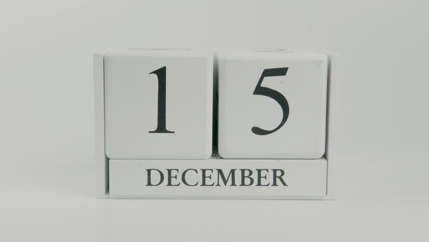 Hand flips a wooden white calendar, changing the date from December 15 to 16, on a clean white background. Perfect for time, schedule, and holiday concepts