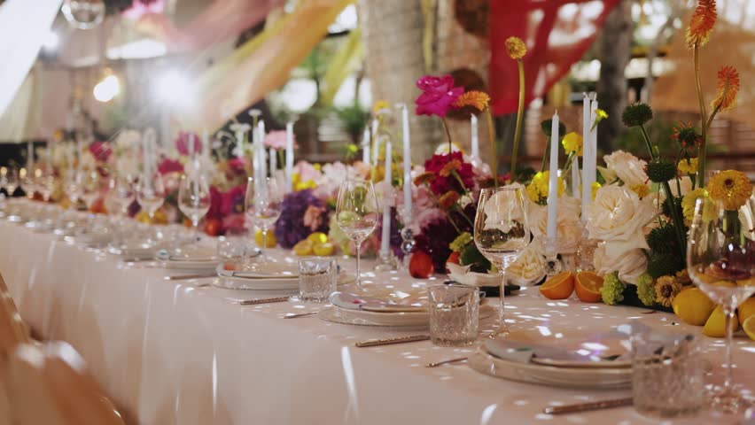 Elegant long dining table at a wedding in a restaurant, festive decor with candles and beautiful flowers. Event decor, decorated tables, table setting.