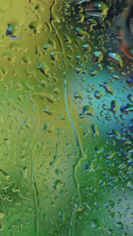 Rain-splattered windowpane with water droplets gently sliding in dim evening light, moody soft focus, ambient atmosphere, soothing scene, perfect for cinematic, introspective, melancholic visuals.