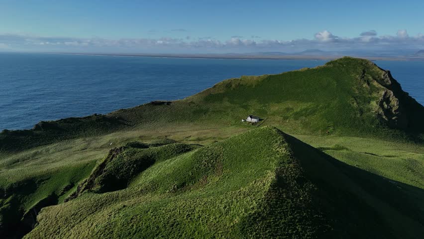 Remote House on Green Hills of Iceland Island by the Ocean Aerial