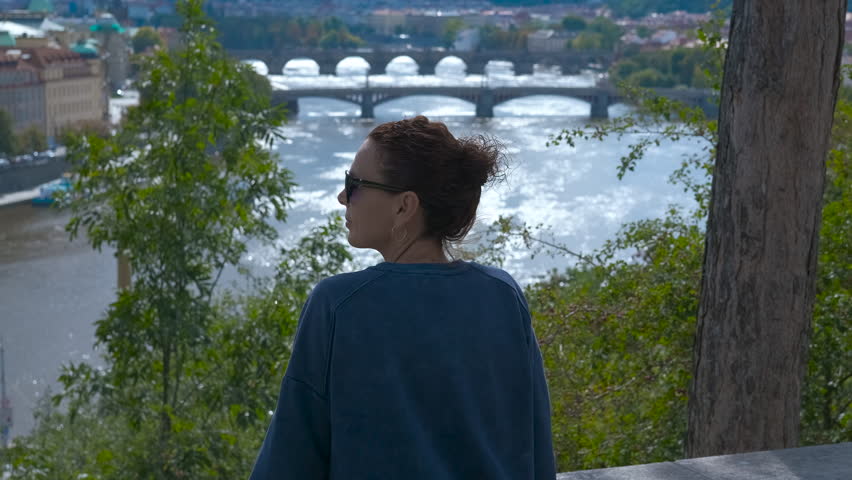 Tourist admiring river and bridges in prague. Contemplative female traveler gazing across historic prague riverscape, panoramic vltava river vista with bridges stretching through urban landscape