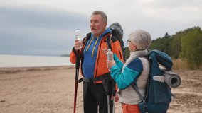 Hiking tourism adventure. Senior couple man woman drinking water enjoying outdoor recreation hiking on beach. Old people backpackers hikers enjoy walking hike trekking active vacation beauty of nature - Powered by Shutterstock - Get 15% off with code: PIKWIZARD15