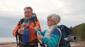 Hiking tourism adventure. Senior couple man woman drinking water enjoying outdoor recreation hiking on beach. Old people backpackers hikers enjoy walking hike trekking active vacation beauty of nature - Powered by Shutterstock - Get 15% off with code: PIKWIZARD15