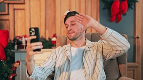 Happy individual enjoys Christmas video call on smartphone, sharing festive cheer. The man smiles, feeling connected and joyful during holiday communication at home. - Powered by Shutterstock - Get 15% off with code: PIKWIZARD15