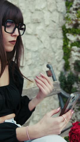 Woman On The Bench Putting The Phone In The Bag And Picking Up Flowers