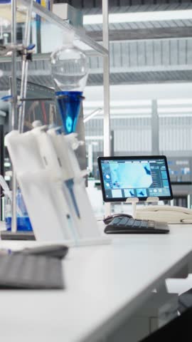 Vertical video Close up of microscope in lab next to computer monitor displaying DNA data and molecular analysis interface in laboratory. Bioinformatics genomics software on PC and optical device in