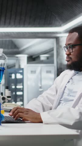 Vertical video Chemical engineer in lab inspecting chemical compounds in vials for purity verification using PC software. Man in laboratory preparing reagent test tubes for assay procedures on