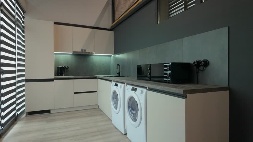 a grey kitchen with marble counter top,a black sink and a kettle,a round grey table and four soft chairs 
