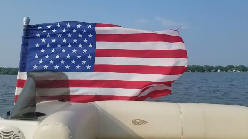 American flag waving on boat speeding across lake water on summer day