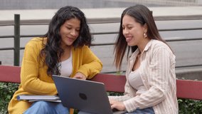 Two young diverse female university students sitting on a bench outdoors. Happy friends studying together, working on a project with a laptop - Powered by Shutterstock - Get 15% off with code: PIKWIZARD15