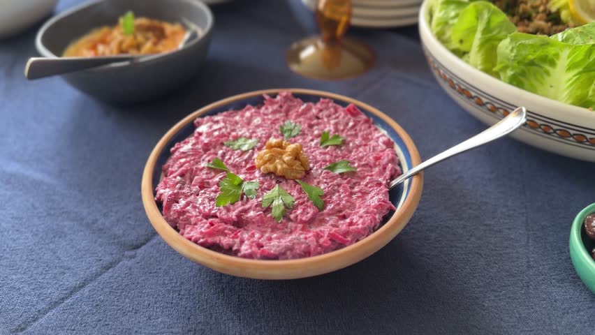 Vibrant Turkish beetroot dip served in a handmade bowl, garnished with walnuts and parsley, part of a traditional Mediterranean meze table.