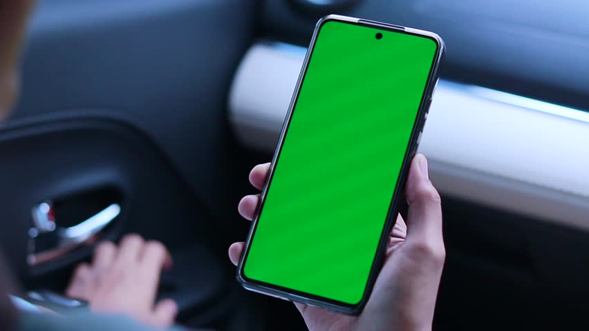 A woman in a car and using her smartphone with green screen
