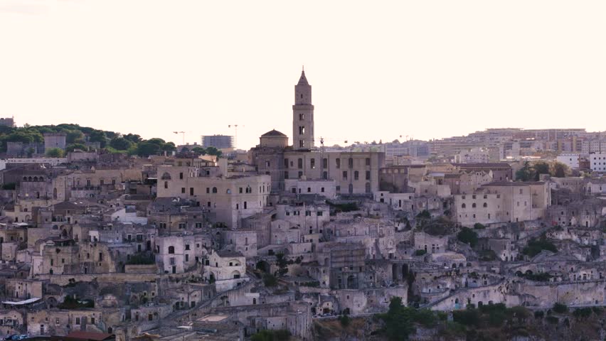Church tower and downtown of Matera city, sun shines from behind, aerial view