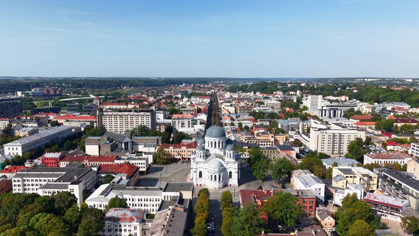 Aerial panoramic view of central Kaunas, Lithuania, featuring the prominent St. Michael the Archangel Church and the long pedestrian Laisvės Alėja stretching into the distance.