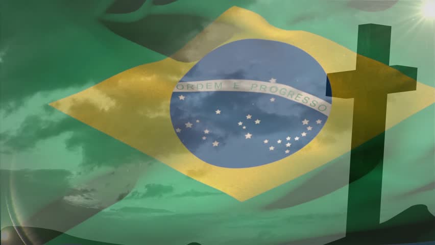 Gentle breeze making Brazilian flag fluttering showing stars and motto over green sky beside cross. Patriotism, spirituality, movement, outdoor, monument, celestial, symbolism