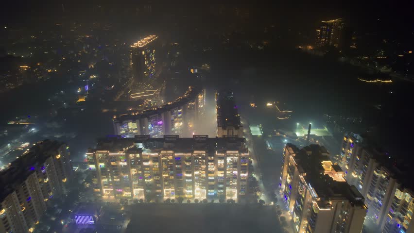aerial drone flying over brightly lit and decorated buildings for diwali with fireworks going all around with delhi cityscape in distance with smoke smog fog pollution over Delhi, Gurgaon, Noida