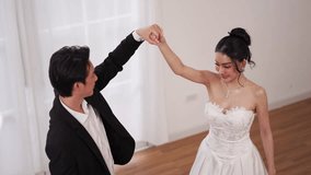 Asian couple having fun dancing together, groom twirls bride in white dress during wedding moment - Powered by Shutterstock - Get 15% off with code: PIKWIZARD15