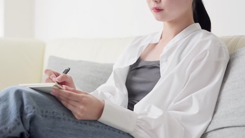 Asian woman taking notes on ideas at home