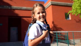 Beautiful elementary school girl with pigtails and a backpack smiling and waving goodbye to her mother before entering the school building on a sunny day, ready for a new day of learning - Powered by Shutterstock - Get 15% off with code: PIKWIZARD15