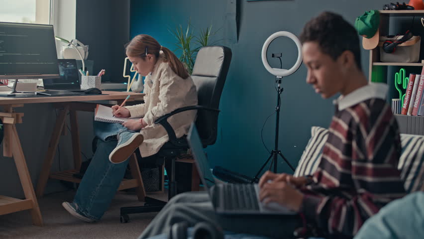 Rack focus of two diverse teenagers studying how to code using digital devices in cozy home workspace - Powered by Shutterstock - Get 15% off with code: PIKWIZARD15