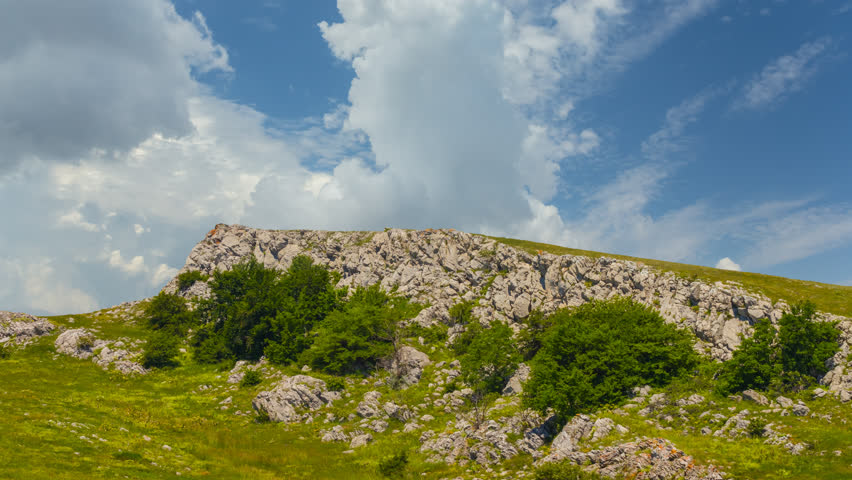 mountain ridge among green hills under blue cloudy sky time lapse scene