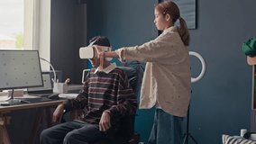 Medium long shot of gen alpha multiethnic girl helping her friend wearing augmented reality goggles sitting at home desk in cozy room - Powered by Shutterstock - Get 15% off with code: PIKWIZARD15