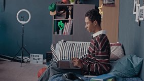 Side view of teenage black boy using wireless laptop while young girl examining virtual reality in AR headset in cozy kids room - Powered by Shutterstock - Get 15% off with code: PIKWIZARD15