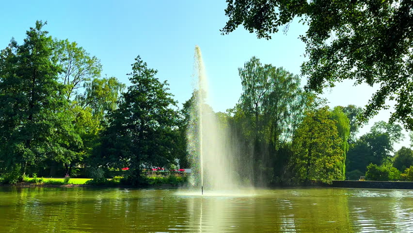 A large fountain in the center of a city lake. A fountain on a lake with a powerful jet that shoots upwards.