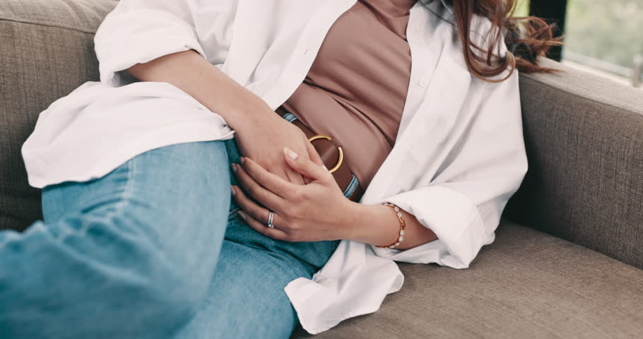 Stomach ache, sick and woman on sofa in home with endometriosis, cramps or constipation. PMS, food poisoning and female person with tummy pain for menstruation or indigestion in living room at house.