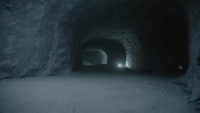 A static, dark shot looking deep down a subterranean salt mine tunnel. The walls are rough salt rock, and faint distant lights illuminate the dusty floor. - Powered by Shutterstock - Get 15% off with code: PIKWIZARD15