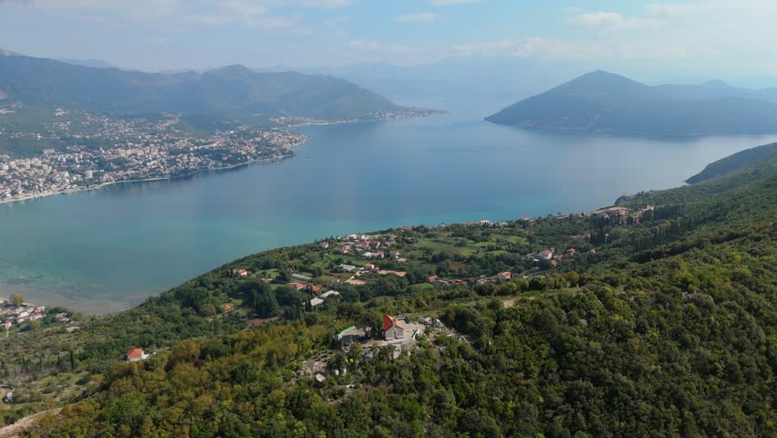 Aerial cinematic view of the Bay of Kotor entrance — Montenegro nature, turquoise sea, and mountains.
