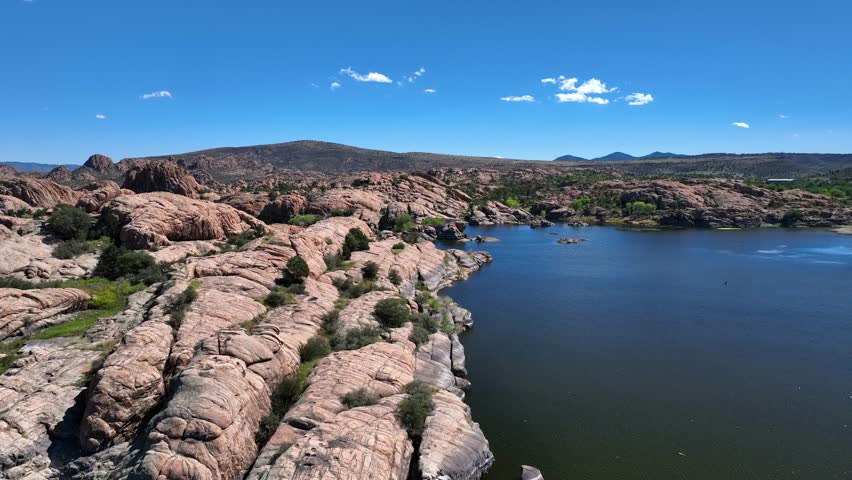 Aerial view of Willow Creek Reservoir, where the dark blue water contrasts with the light brown rock formations, creating a serene landscape, Willow Creek, Arizona, United States.