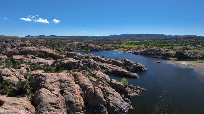 Aerial view of the scenic willow creek reservoir surrounded by rocky terrain and sparse greenery under a clear blue sky, Willow Creek, Arizona, United States.