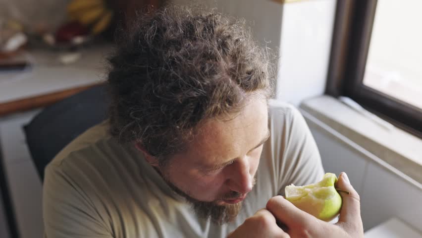 Man savoring every bite of a sour green apple