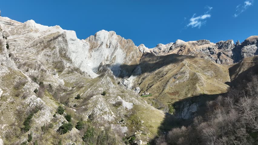 Aerial view of mountain ranges with contrasting light and shadows under a blue sky, creating a stunning landscape, Tuscany, Italy.