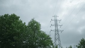 Static shot of a power line tower next to green trees in Stockholm. The sky is overcast with thick clouds. - Powered by Shutterstock - Get 15% off with code: PIKWIZARD15