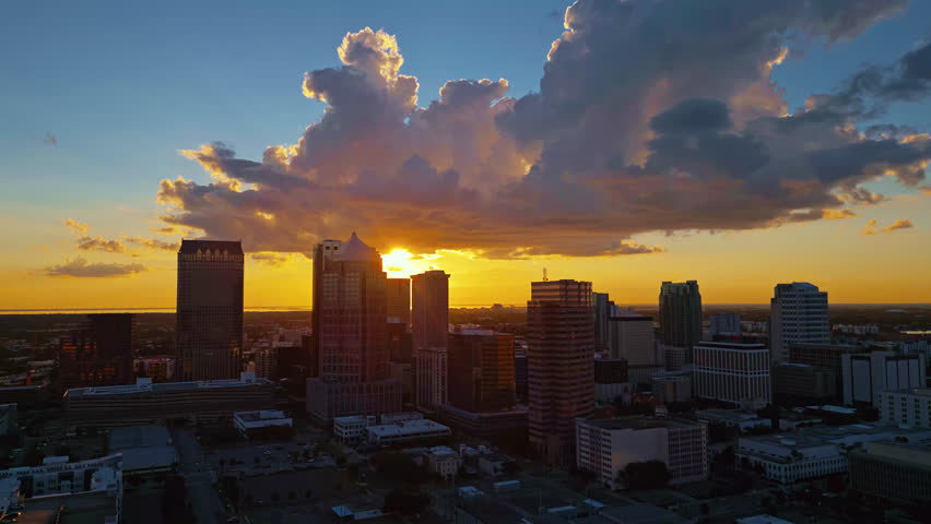 Glowing Tampa skyline at golden hour. A sweeping aerial tracking shot of the city
