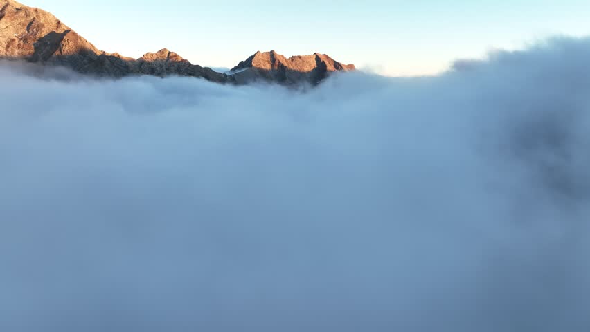 Aerial view of mountain peaks piercing through a sea of swirling clouds, creating a serene yet dramatic landscape, Resceto, Tuscany, Italy.
