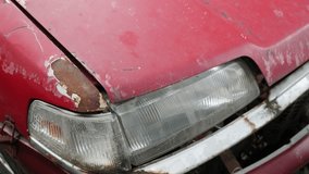 Severe rust corrosion and peeling paint damage on red car hood edge above headlight showing metal deterioration - Powered by Shutterstock - Get 15% off with code: PIKWIZARD15