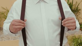 Close up of man adjusting suspenders on white dress shirt before event - Powered by Shutterstock - Get 15% off with code: PIKWIZARD15