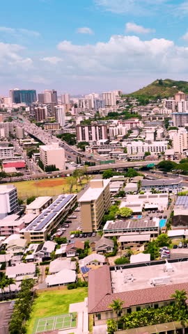 Aerial view of Honolulu, Oahu showing residential and commercial buildings, solar panels, and a distinct green peak in the background. Vertical video.