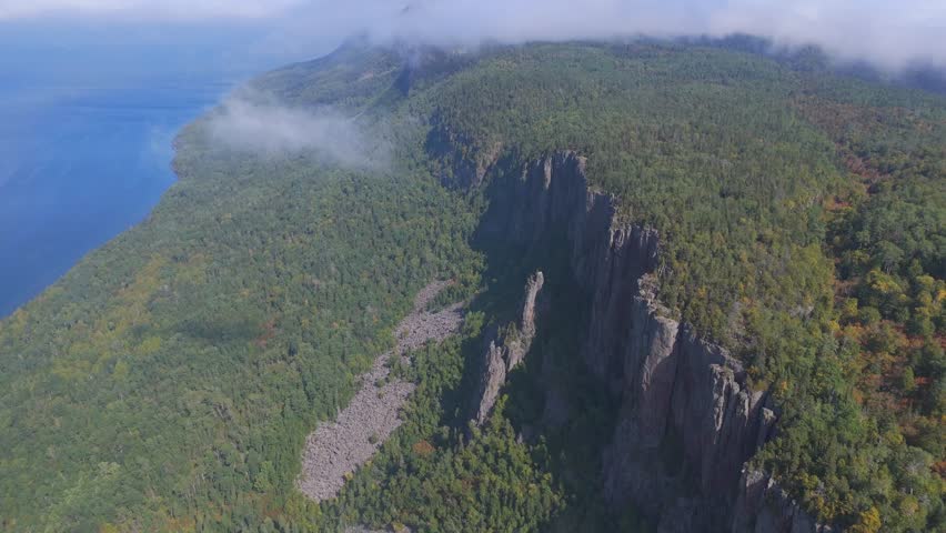 A stunning view of the towering cliffs at Sleeping Giant, Ontario, surrounded by dense green forest overlooking the vast expanse of Lake Superior.