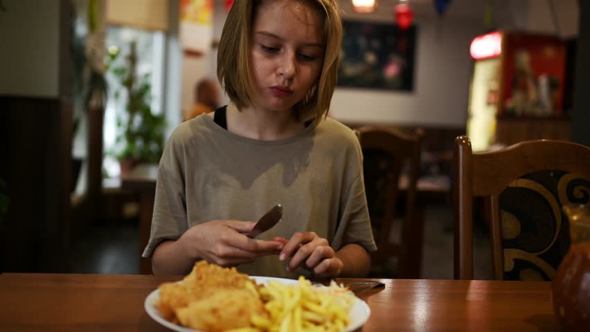 Teenage Girl Eating Fries And Meat In A Restaurant