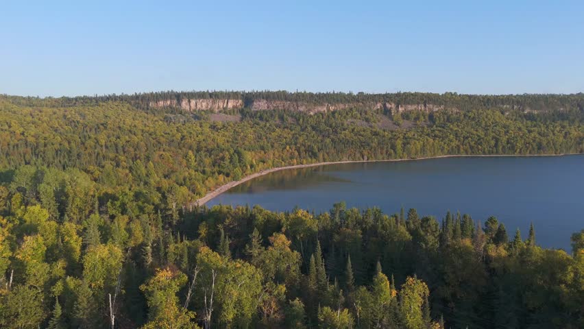 Golden hour light illuminates the forest along Lake Superior’s Ontario coast at Sleeping Giant Provincial Park casting long shadows and a radiant glow across the tranquil landscape.