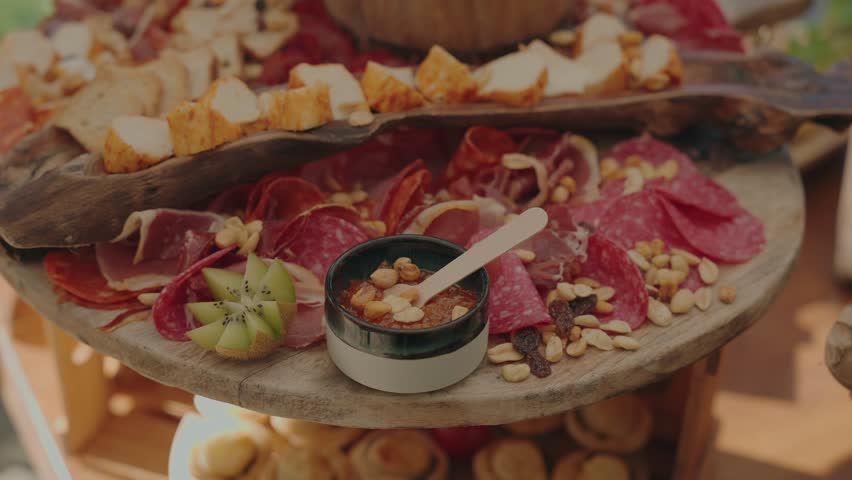 Rustic charcuterie platter featuring assorted cured meats, cheese cubes, nuts, and dipping sauce