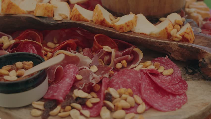Assorted cured meats, cheese slices, and nuts arranged on a wooden charcuterie board