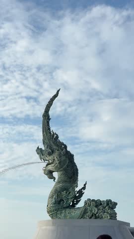 The iconic Naga Serpent  statue at Songkhla province, Southern Thailand, spouting water into the sea. This footage photo captures the landmark against a beautiful sky, representing a blend of traditi