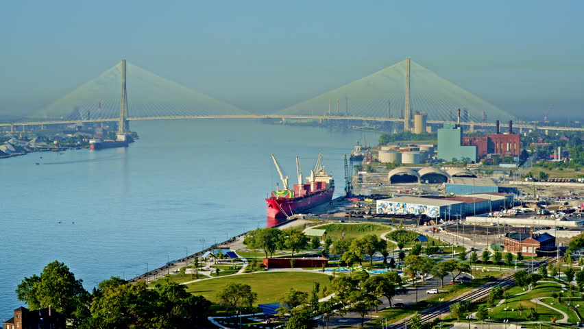 Scenic drone view of Detroit River with city skyline and large freighter making its way downstream.