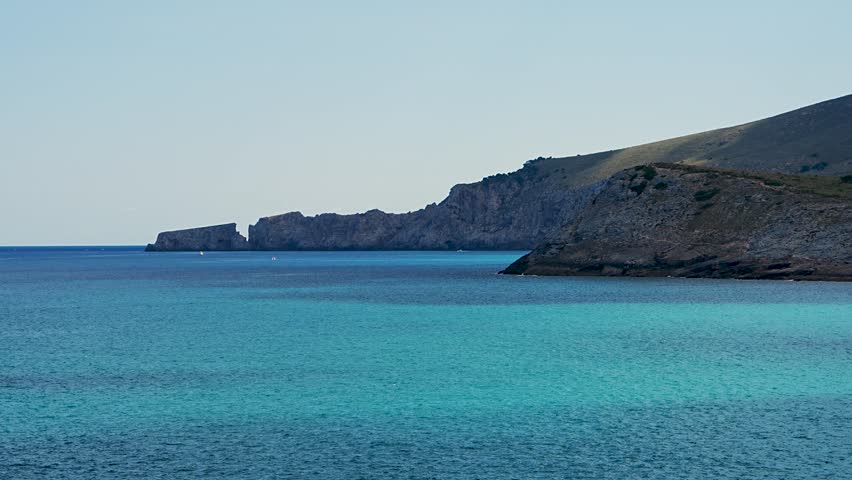 Beautiful rocky shore and crystal clear turquoise water at Cala Torta beach, Mallorca, Spain. Scenic Mediterranean coastal landscape under bright sunlight