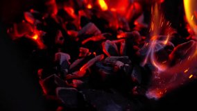 Smoldering charcoal embers glowing under fading flames inside dark outdoor barbecue, slow motion - Powered by Shutterstock - Get 15% off with code: PIKWIZARD15
